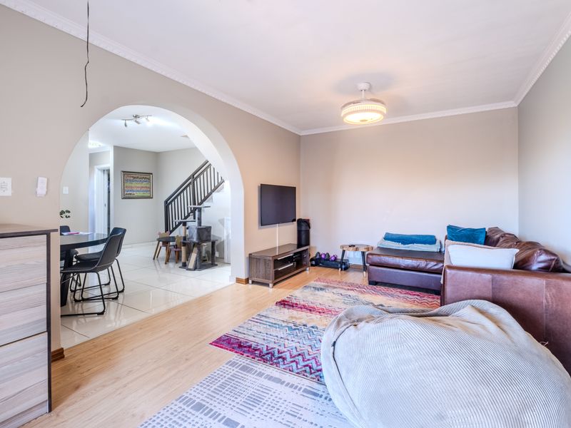 Spacious living area featuring laminate flooring, an elegant archway leading to the dining space, and a ceiling fan, creating a comfortable and open atmosphere.