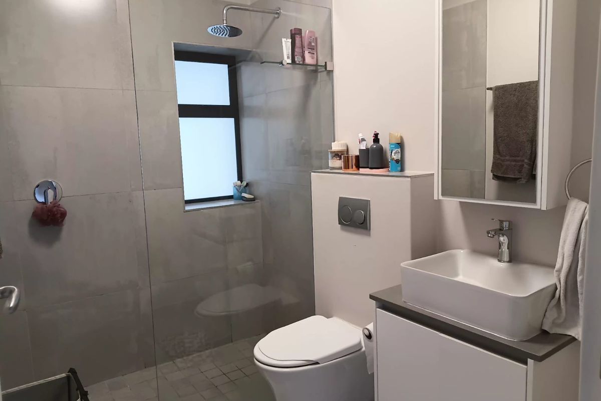 Modern bathroom featuring a walk-in shower with glass screen, wall-mounted toilet with concealed cistern, and a contemporary vessel sink vanity unit.