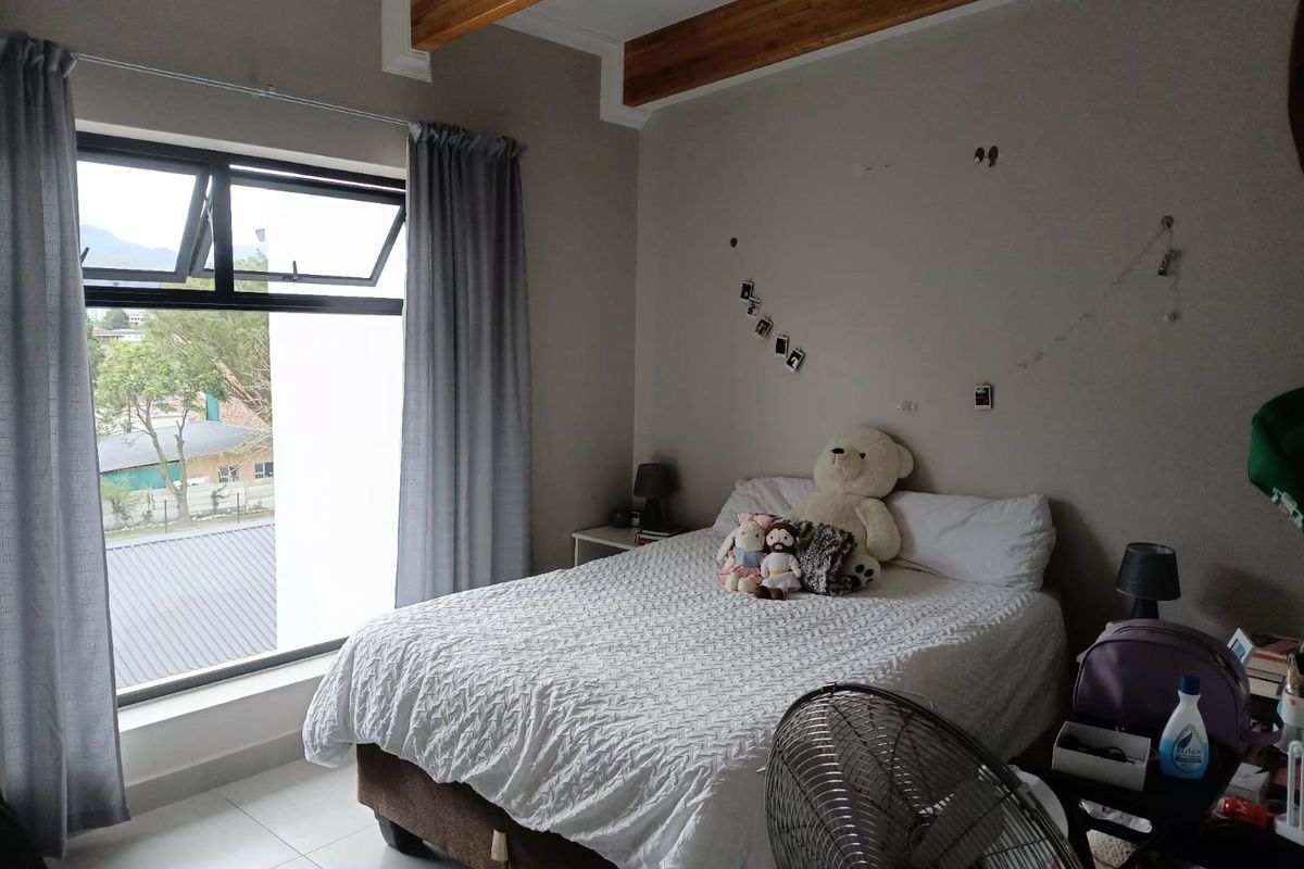 A bedroom featuring exposed timber ceiling beams, tiled flooring, and an aluminium window frame with views of the surrounding area.