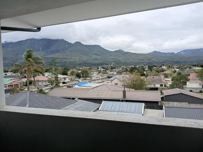 A scenic elevated view overlooking a residential neighborhood with prominent mountain vistas in the background, captured from a balcony.
