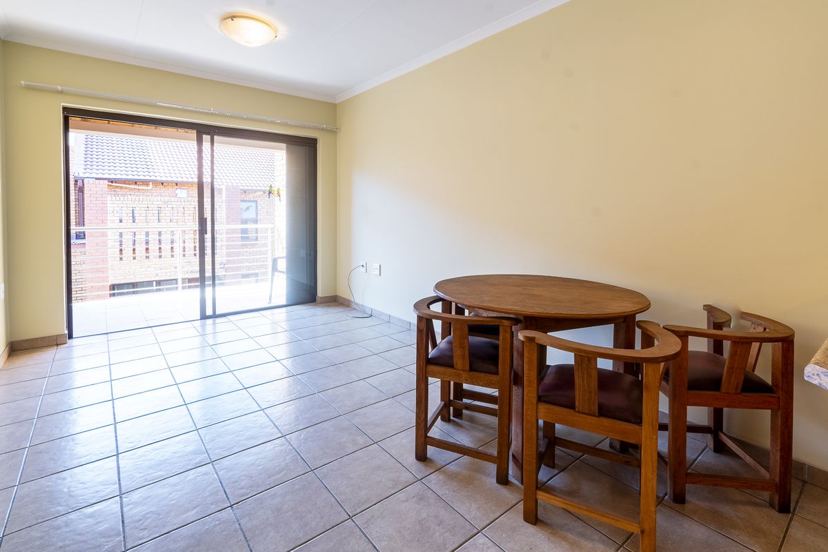 A bright living area featuring tiled flooring and a large sliding glass door that provides access to an outdoor balcony.