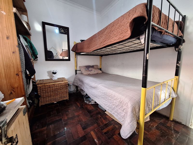 A compact bedroom featuring traditional parquet flooring and coved ceilings, currently utilized with bunk bed configuration.