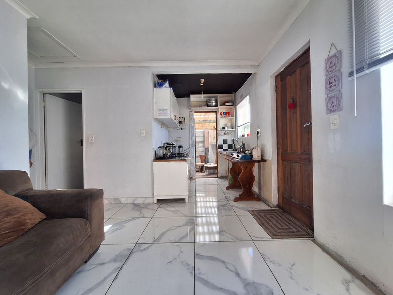Open plan living and kitchen area featuring marble-look tiled flooring and direct access to a secondary utility space.