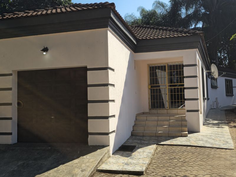 Front elevation of a residential property featuring a single garage, tiled roof, and paved driveway with security gate access.