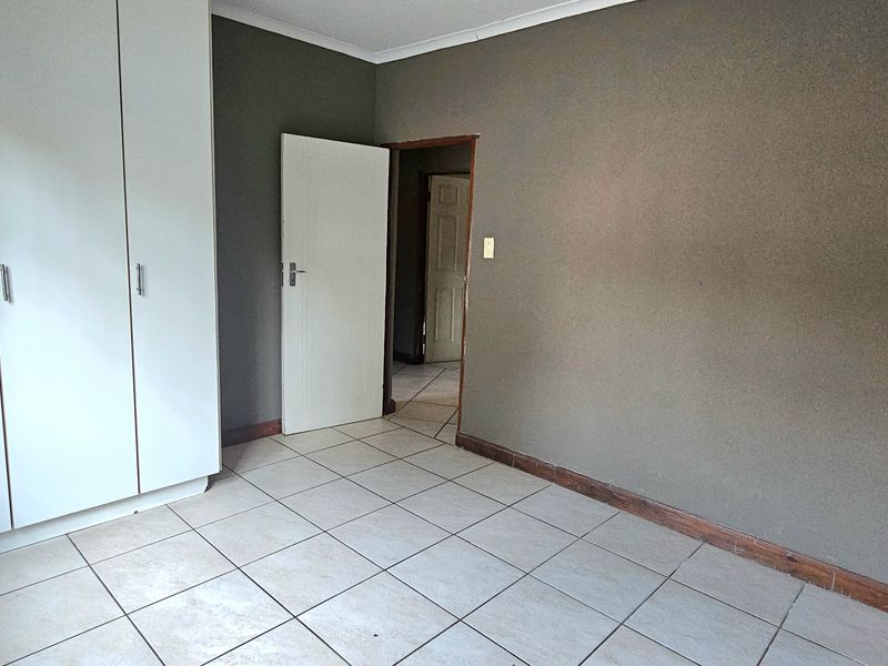 An empty bedroom featuring tiled flooring and built-in cupboards, offering a neutral canvas ready for personalization.
