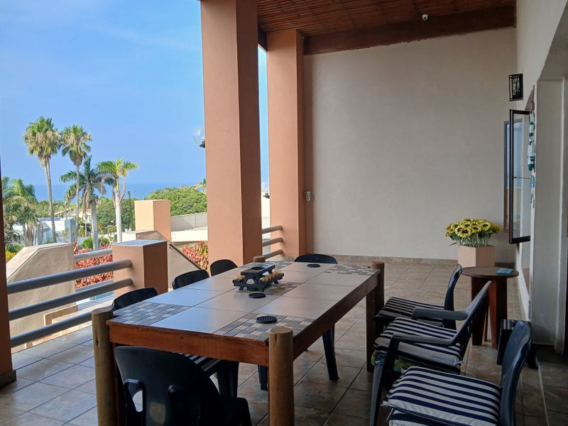 Spacious covered patio featuring tiled flooring, timber ceiling, and support columns, offering an open-air space with scenic views.