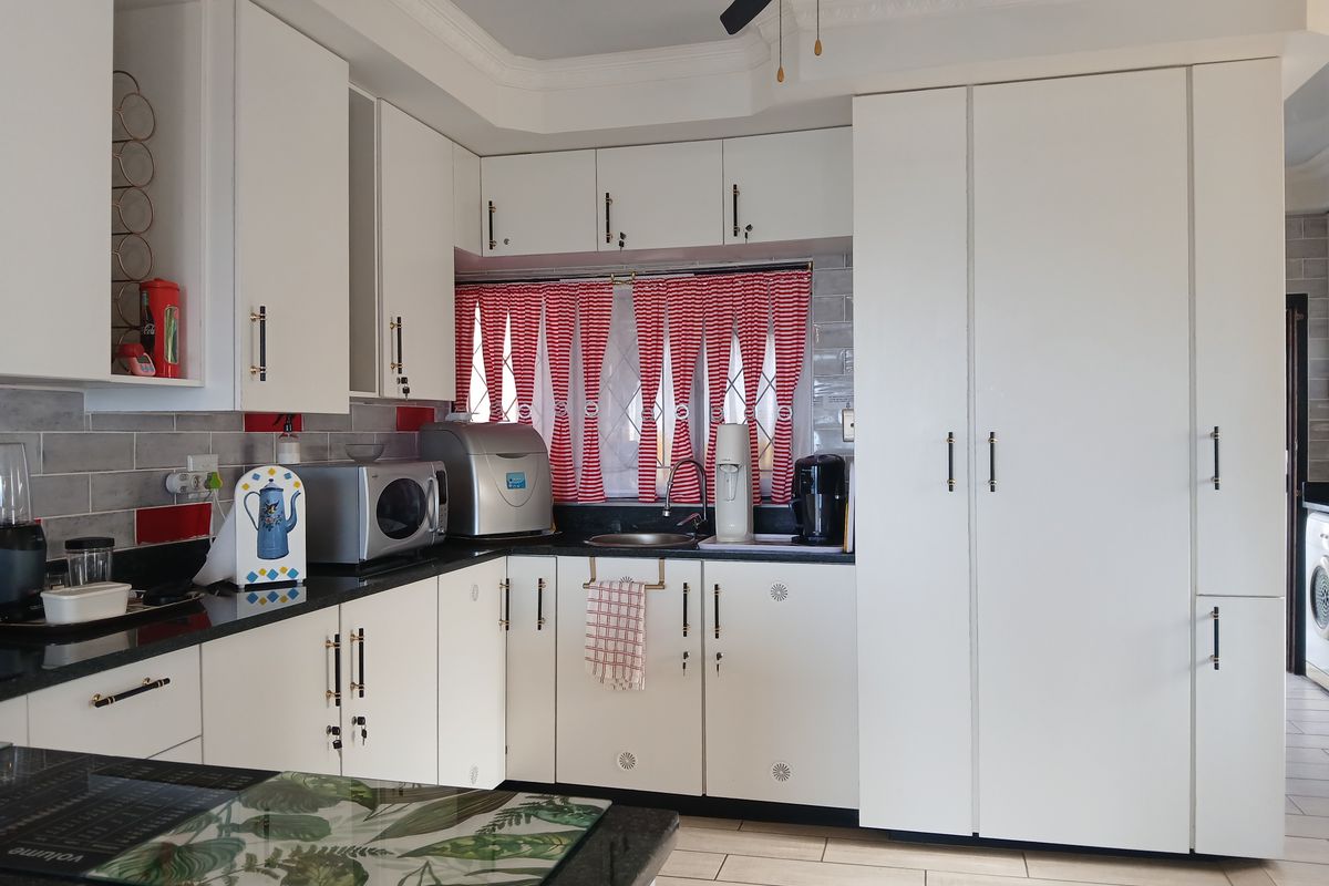 A well-maintained kitchen featuring white cabinetry, dark granite countertops, subway tile backsplash, and tiled flooring with integrated storage solutions.
