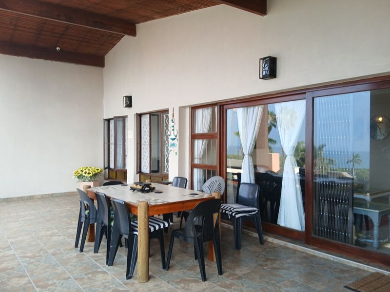 Spacious covered patio featuring a timber-clad ceiling, tiled flooring, and large sliding glass doors providing seamless indoor-outdoor flow.