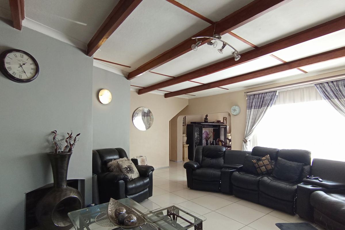 Spacious living room featuring exposed timber ceiling beams, tiled flooring, and a recessed fireplace, offering a comfortable and characterful living space.