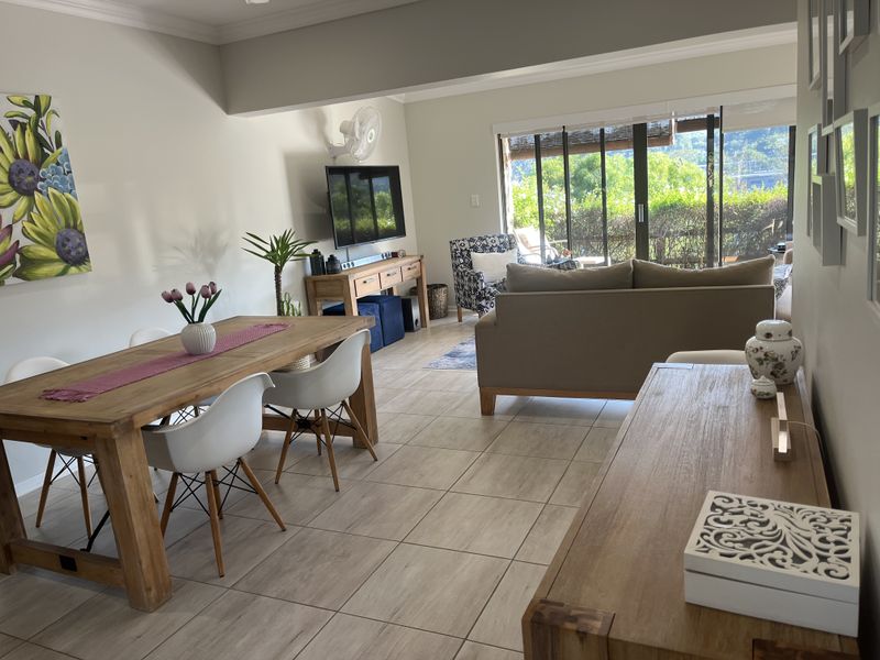 Spacious open-plan living and dining area featuring neutral tiled flooring, crown molding, and large sliding glass doors providing access to the outdoor space.