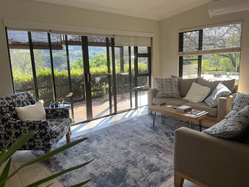 Bright and airy living room featuring large sliding glass doors, tiled flooring, and a split-system air conditioner, offering pleasant views of the garden.