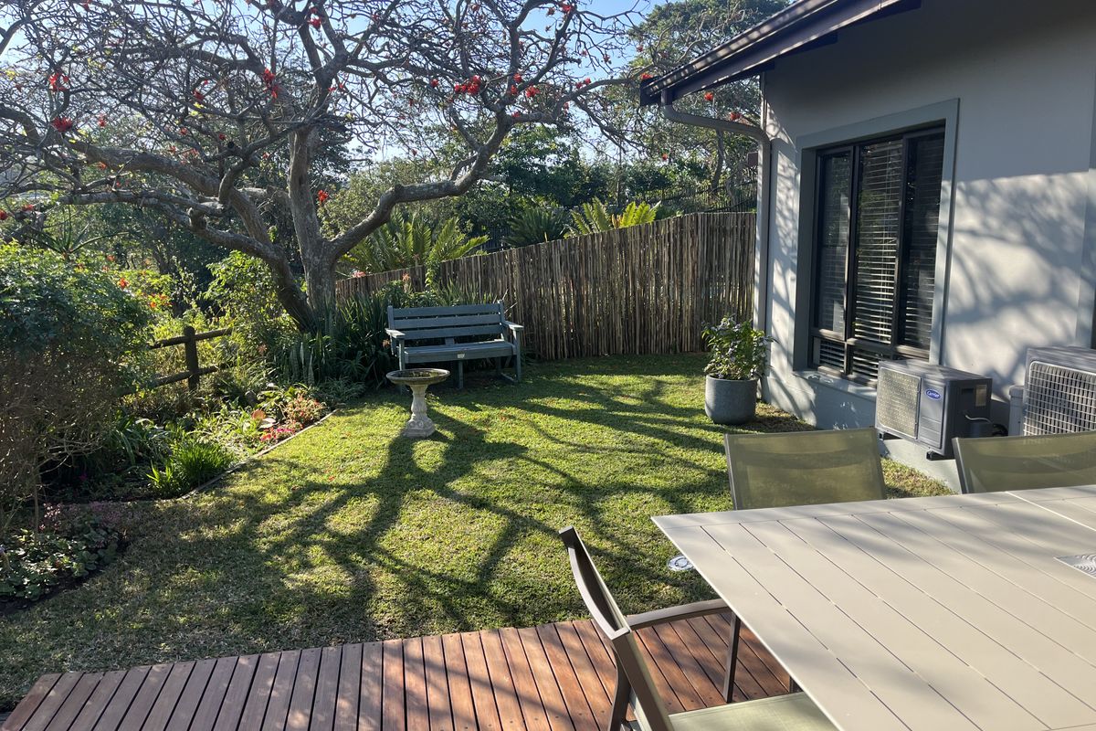 A well-maintained rear garden featuring timber decking, established trees, and bamboo fencing, providing a private and tranquil outdoor space.