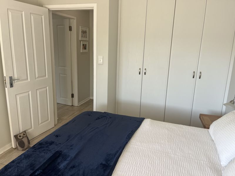 A well-maintained bedroom featuring neutral walls, tiled flooring, and ample built-in cupboard storage space.