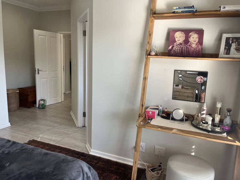 A bedroom interior featuring tiled flooring, neutral wall finishes, and access to an adjacent hallway through internal doors.