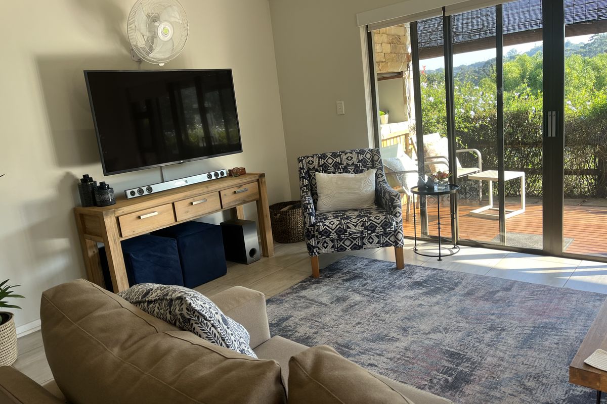 A comfortable living room featuring tiled flooring and large sliding glass doors that provide direct access to an outdoor patio area.