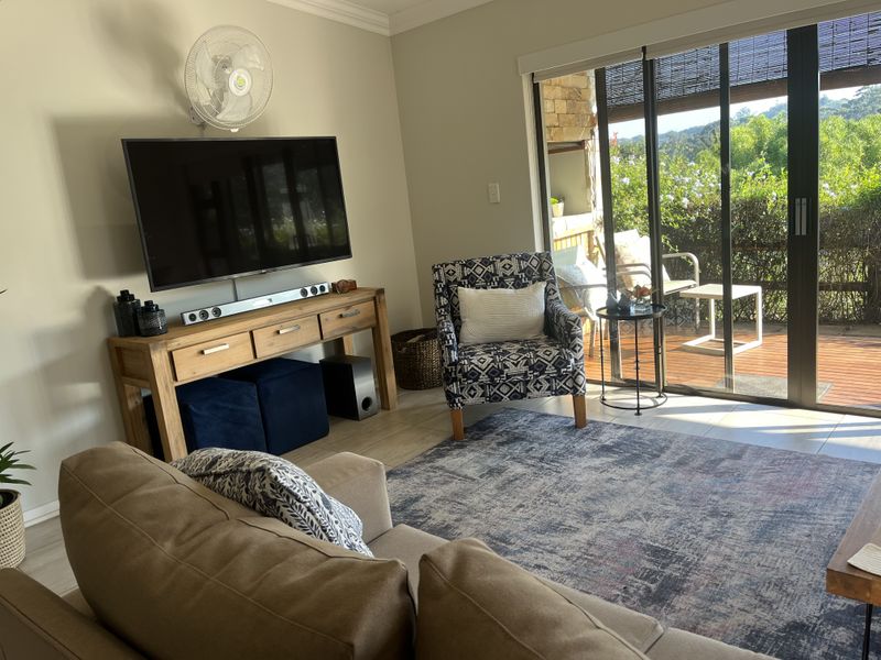 A comfortable living room featuring tiled flooring and large sliding glass doors that provide direct access to an outdoor patio area.