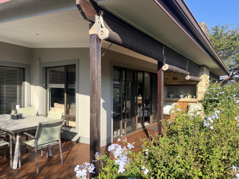 A covered patio featuring timber decking, built-in braai, and sliding glass doors, providing a seamless transition between indoor and outdoor living spaces.