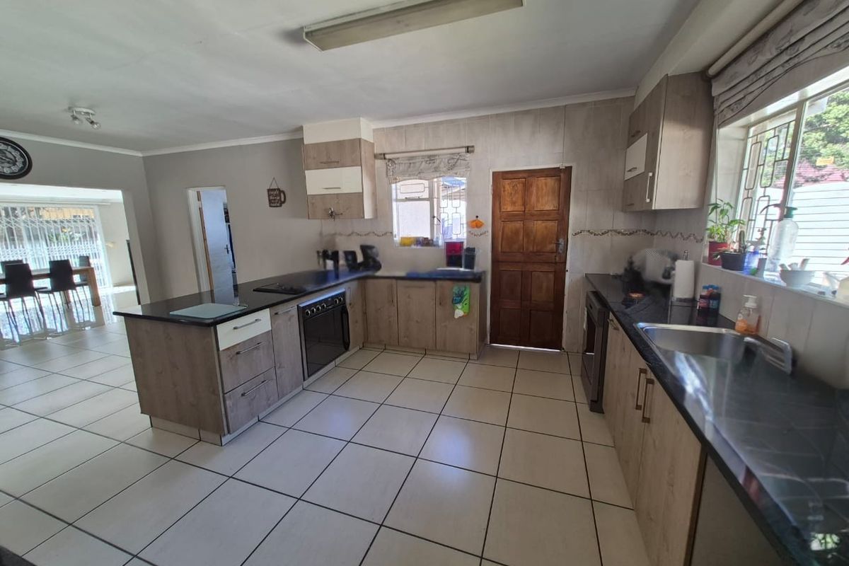 Functional kitchen featuring wood-look cabinetry, granite countertops, built-in oven, and tiled flooring, with an open-plan layout connecting to the dining area.