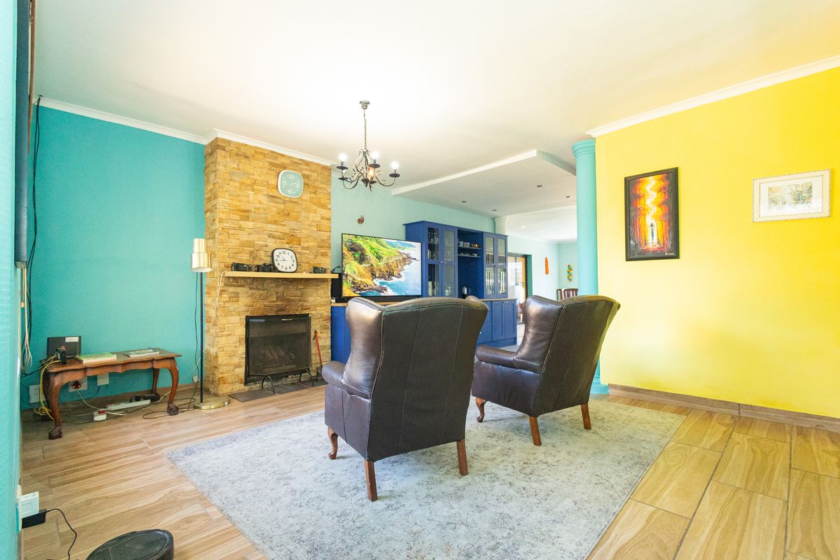Living room featuring a stone-clad fireplace, built-in cabinetry, and tiled flooring, offering a distinct layout with vibrant wall finishes.