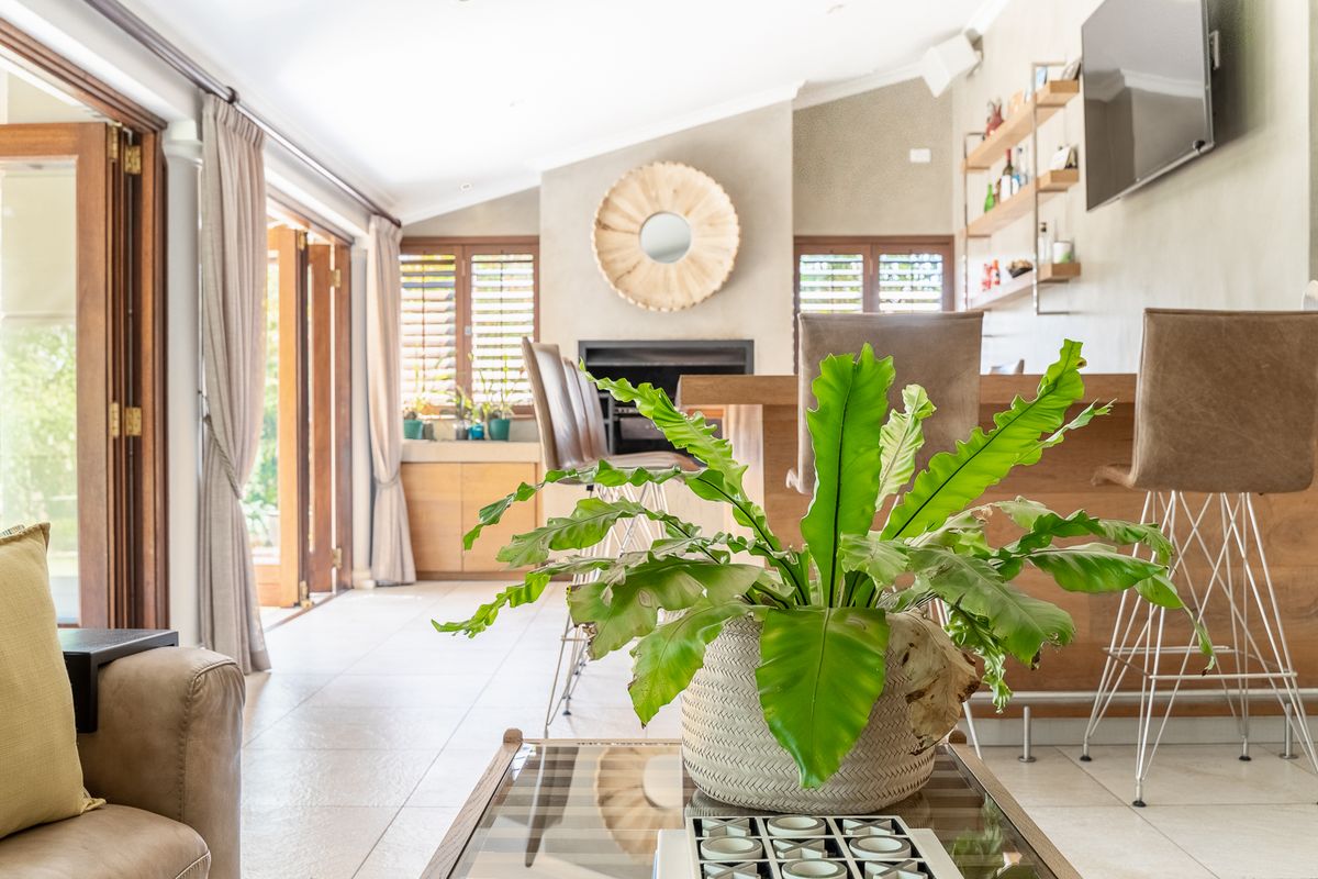 Spacious living area featuring tiled flooring, a built-in fireplace, timber shutters, and a custom bar counter with direct access to the outdoor patio.