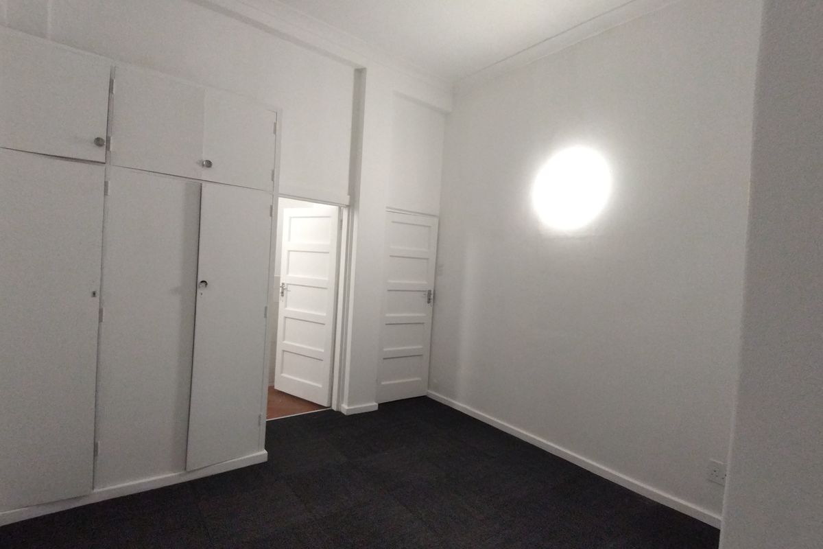 An empty bedroom featuring built-in cupboards, carpet flooring, and white painted walls with coving detail.