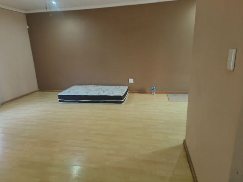 A spacious, empty bedroom featuring light-toned laminate flooring and neutral-colored walls, providing a blank canvas for personalization.