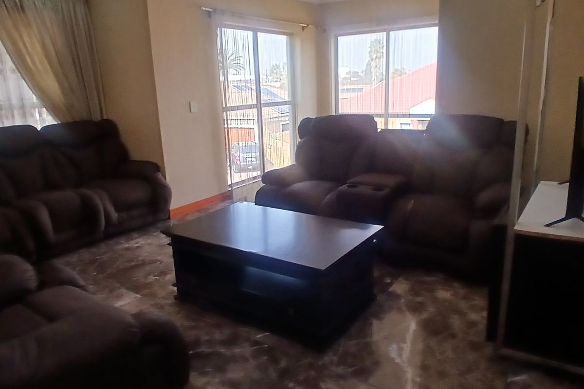 A living room featuring tiled flooring and large windows that provide natural light, offering a comfortable space for relaxation.