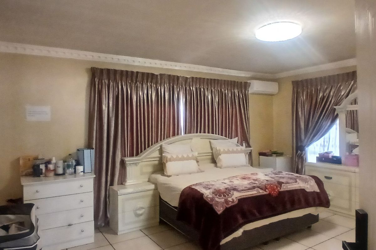 A bedroom featuring tiled flooring, crown molding, and a wall-mounted split-system air conditioning unit.