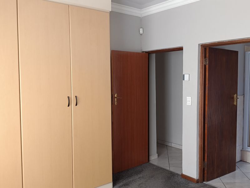 A bedroom featuring built-in cupboards, carpeted flooring, and direct access to an en-suite bathroom with tiled flooring.