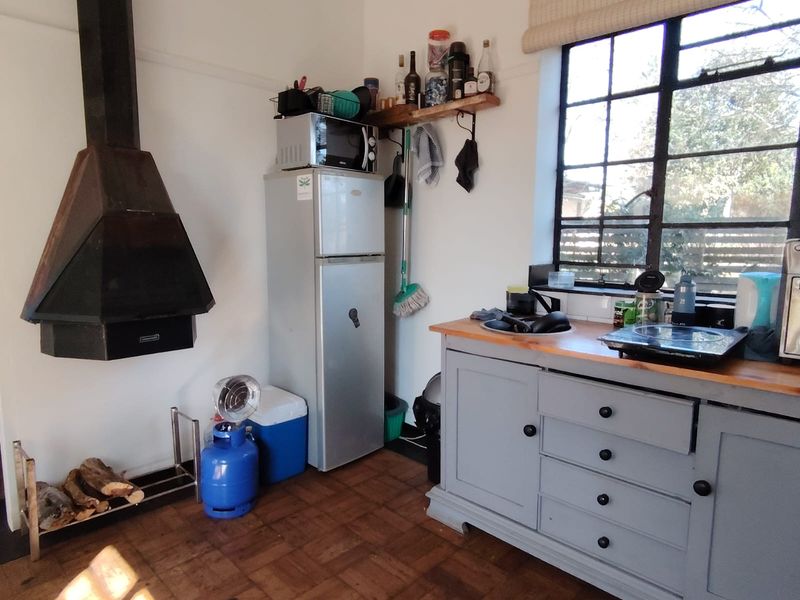 Compact kitchen area featuring a suspended fireplace, timber parquet flooring, and painted cabinetry with a timber countertop.