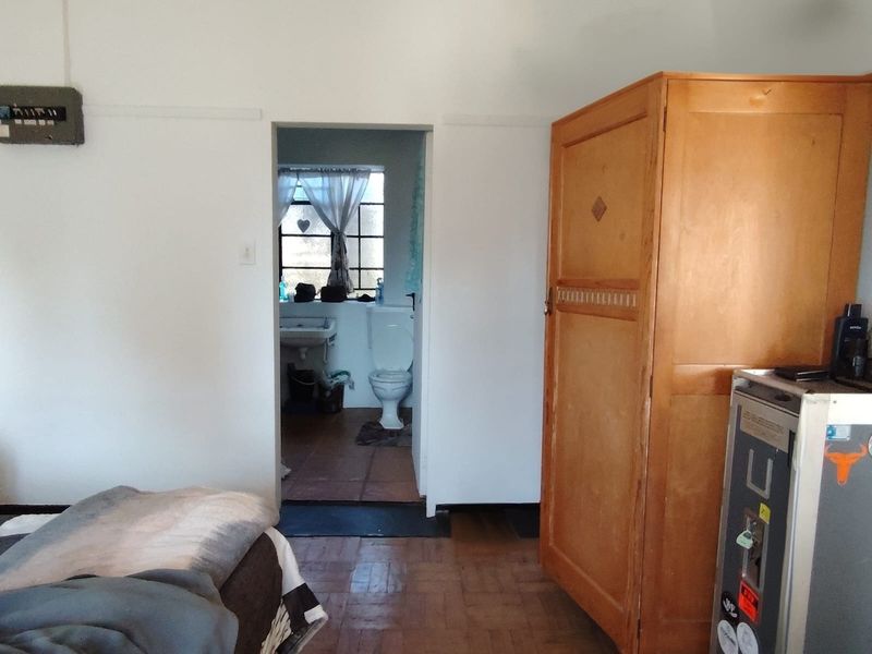 Bedroom featuring original parquet flooring and direct access to an en-suite bathroom, offering a functional layout with potential for cosmetic updates.