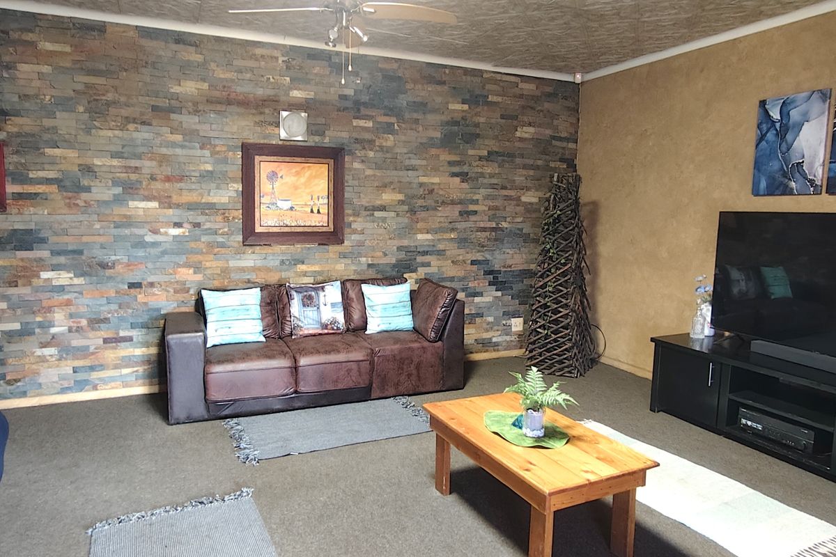 A living room featuring a prominent stone-clad feature wall and a ceiling fan, providing a textured focal point for the space.