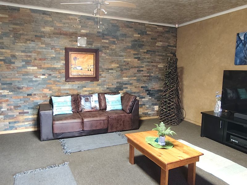 A living room featuring a prominent stone-clad feature wall and a ceiling fan, providing a textured focal point for the space.