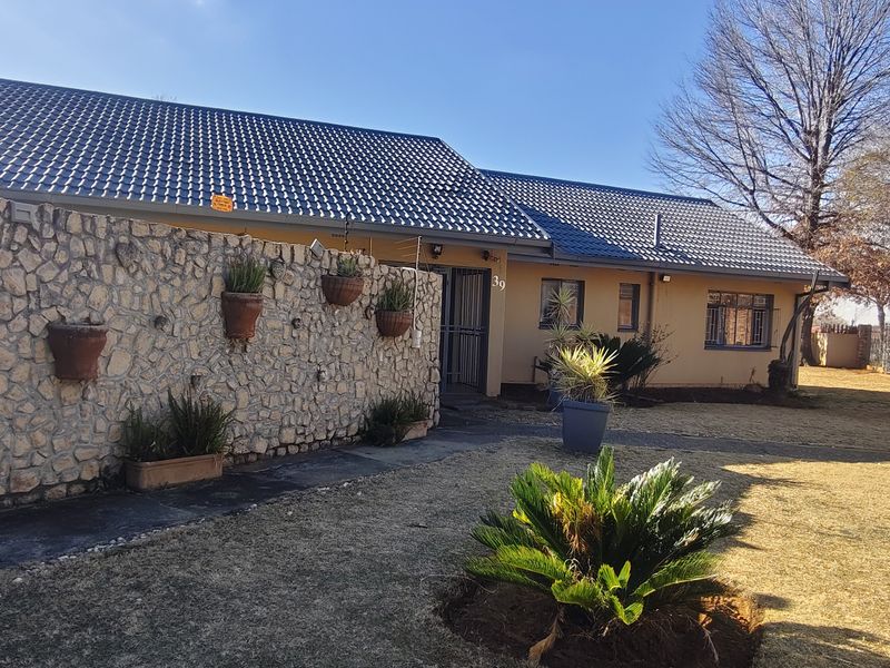 Front elevation of a single-story house featuring stone cladding, a tiled roof, and a paved entrance walkway.