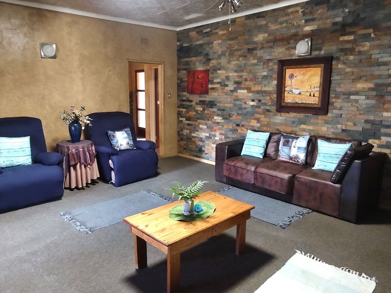 Spacious living room featuring a prominent stacked stone accent wall and textured plaster finishes, offering a warm and rustic aesthetic.
