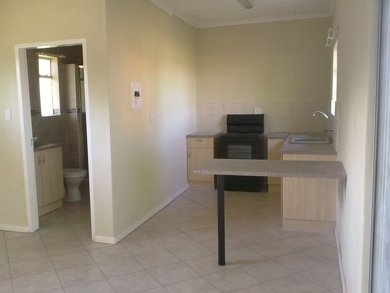 Open plan kitchen area featuring built-in cabinetry, a breakfast bar, and tiled flooring, with an adjacent bathroom visible.