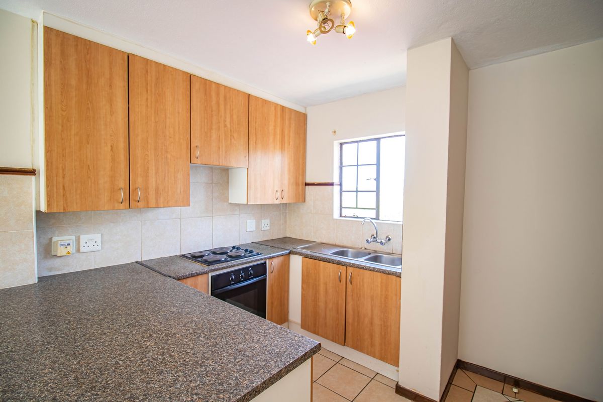 A functional kitchen featuring laminate cabinetry, a built-in electric oven and hob, double stainless steel sink, and tiled backsplash.