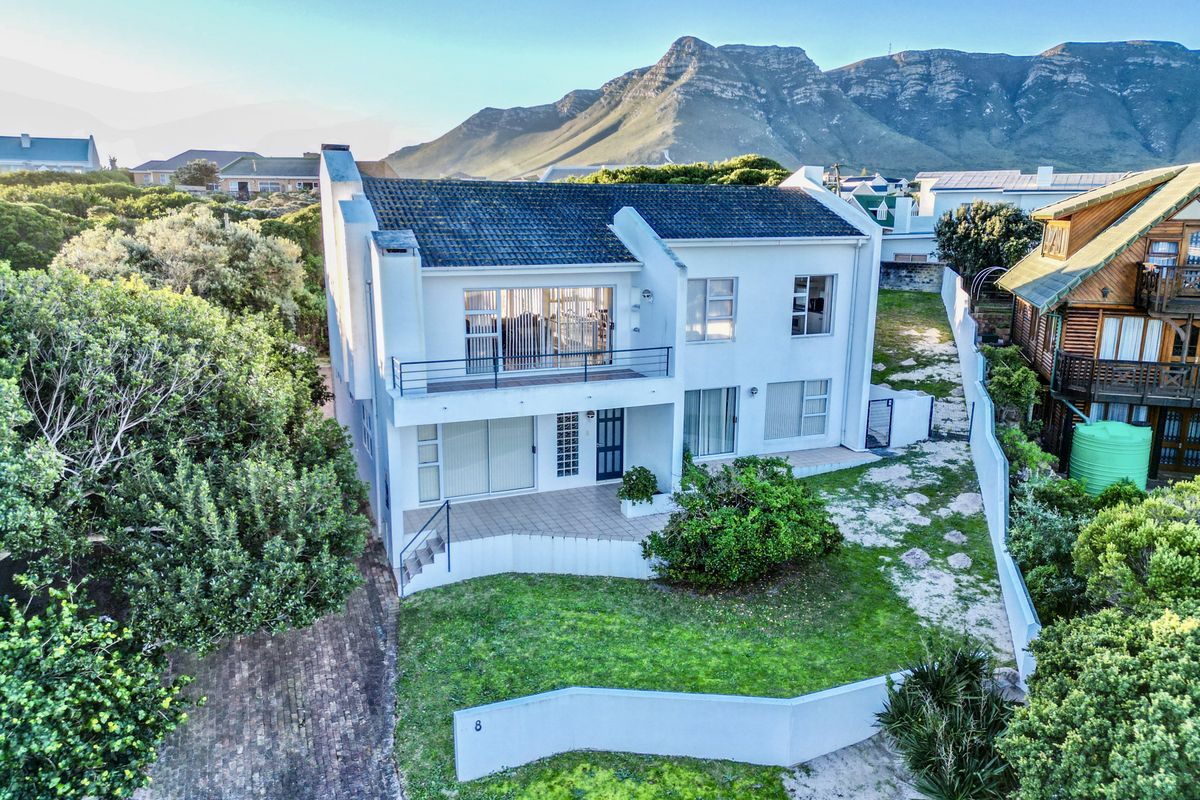 Aerial view of a two-story residential property featuring a tiled roof, balcony, paved patio, and a landscaped garden with mountain views.