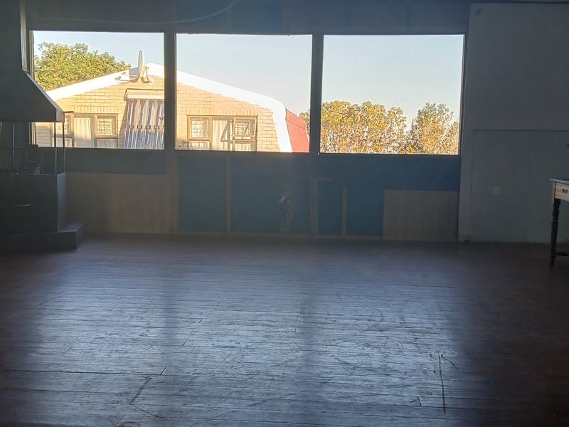Spacious living area featuring a built-in fireplace, large windows with natural light, and timber flooring, currently in need of renovation and finishing.