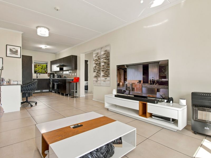 An open-plan living and kitchen area featuring tiled flooring, modern dark cabinetry, and a functional layout suitable for contemporary apartment living.