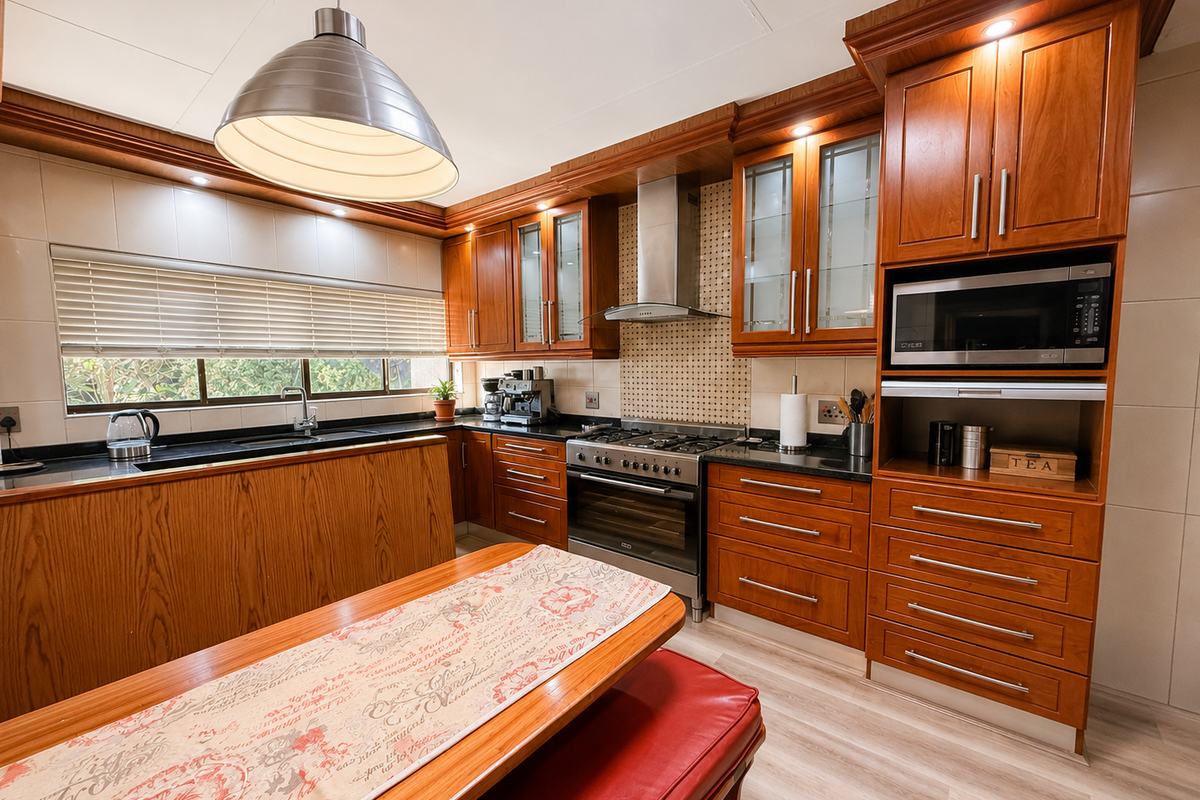 A well-maintained kitchen featuring warm wooden cabinetry, granite countertops, integrated stainless steel appliances, and ample storage space with a functional layout.