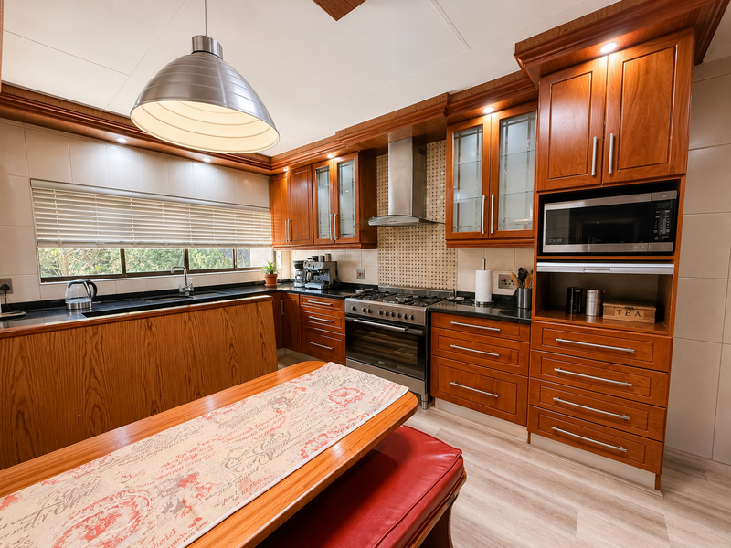 A well-maintained kitchen featuring warm wooden cabinetry, granite countertops, integrated stainless steel appliances, and ample storage space with a functional layout.