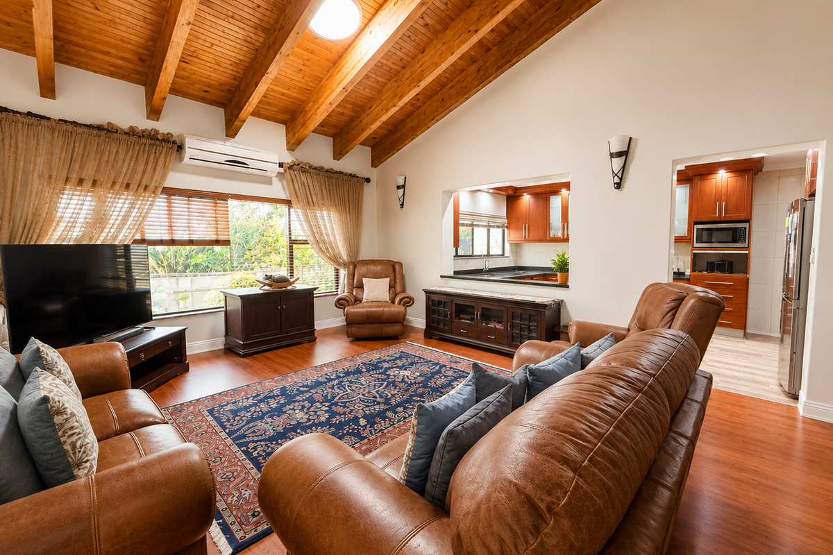 Spacious living room featuring high vaulted timber ceilings, a skylight, and a convenient pass-through window connecting to the adjacent kitchen area.