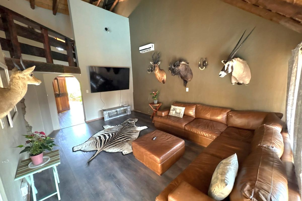 Spacious living room featuring high vaulted ceilings with exposed timber rafters, laminate flooring, and a mezzanine level overlooking the main lounge area.