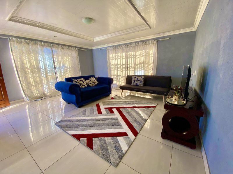 A bright living room featuring large sliding glass doors, polished tiled flooring, and decorative ceiling molding, offering a spacious and well-lit area.
