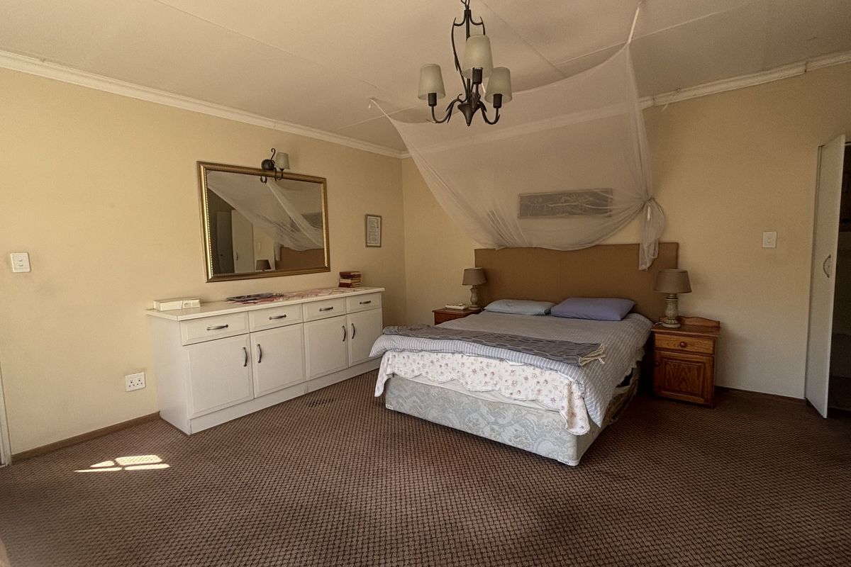 Spacious bedroom featuring neutral walls, carpet flooring, built-in cabinetry, and a central ceiling light fixture.