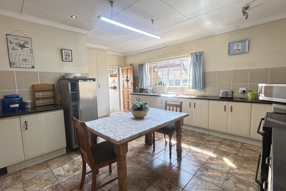 A functional kitchen featuring laminate cabinetry, granite countertops, tiled backsplash, and tiled flooring, offering a practical layout with ample storage space.