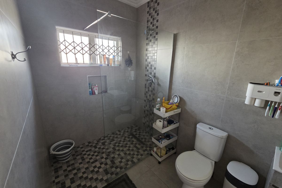 Modern bathroom featuring a walk-in shower with a glass screen, mosaic tile accents, a recessed niche, and a standard toilet.