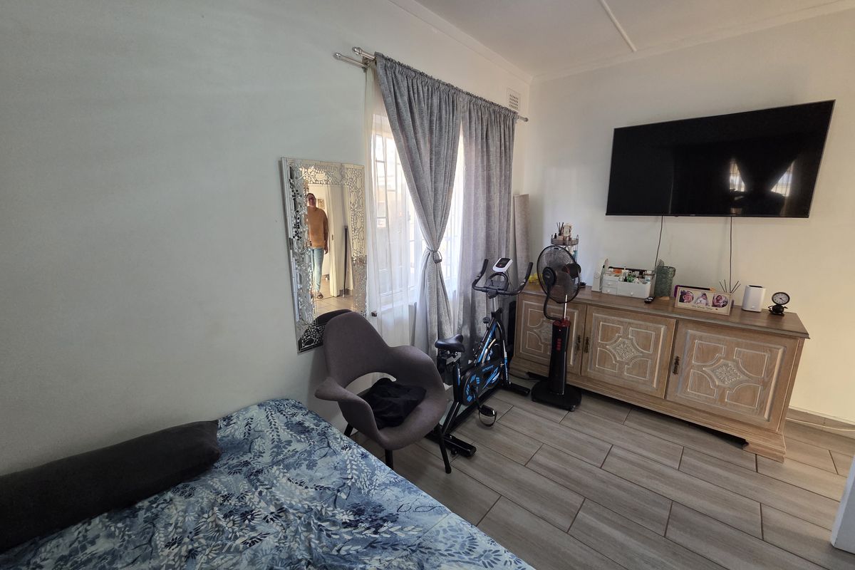 A bedroom featuring tiled flooring and window treatments, currently utilized as a multi-purpose living and exercise space.