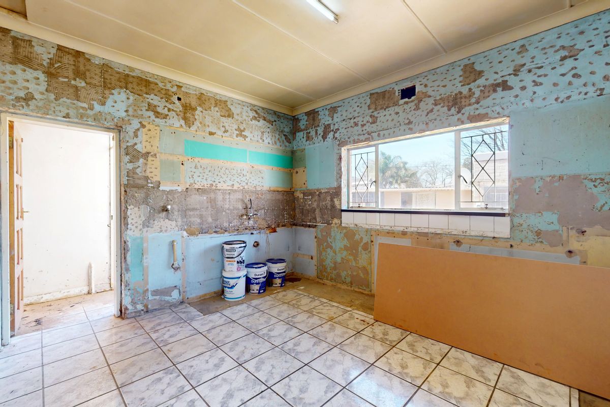 A kitchen space currently undergoing renovation, featuring tiled flooring and exposed wall surfaces, ready for new cabinetry and finishes.